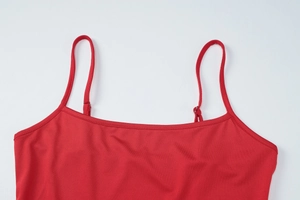 Detail of red camisole top featuring adjustable shoulder straps and flat neckline design