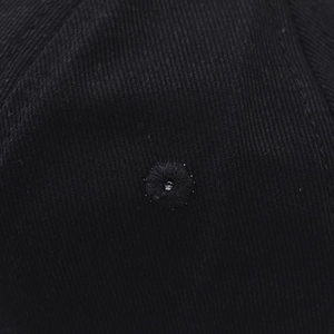 Detailed close-up of the breathable stitched eyelet on a black cotton twill baseball cap