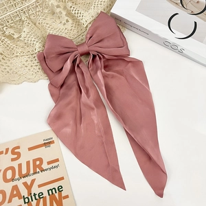 Detail of elegant dusty pink satin bow hair clip with long ribbons on lace background