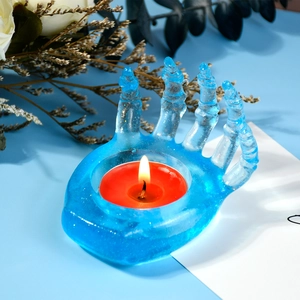 Detail showing hand-shaped candle holder made of blue translucent glitter resin