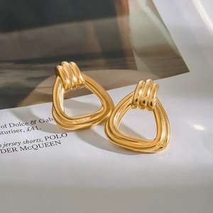 Close-up of polished gold triangular earrings on a stylish fashion magazine background