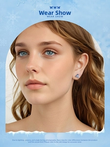 Close-up of elegant blue flower earrings with crystals worn by a model in winter theme