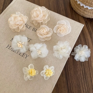 Dettaglio di accessori floreali in chiffon fatti a mano in tonalità crema tenui