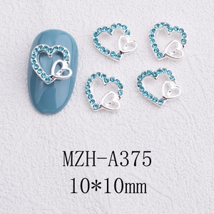 Macro view of blue heart-shaped nail charms with silver hollow bow for manicure art