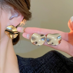 Close-up of irregular gold-plated round earrings worn to show fashion minimalist style