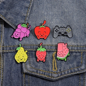 Creative cat and fruit enamel pin collection displayed on a blue denim jacket pocket