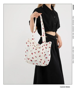 Detail of white corduroy tote bag with red strawberry print and sturdy shoulder straps