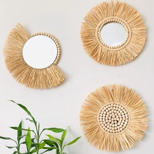 Dettaglio decorazione murale boho con specchi intrecciati in rafia e perle di legno
