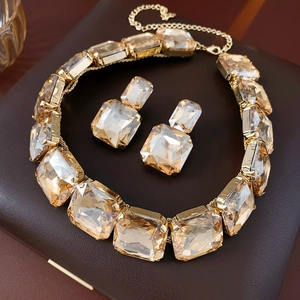 Detailed view of champagne crystal necklace and earring set on brown leather surface