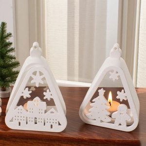 Close-up of matte white ceramic triangle candle holders with Christmas cutout patterns