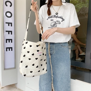 Detail of a beige canvas tote bag with black heart patterns in a street setting