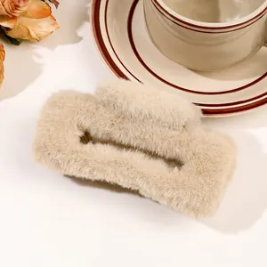 Macro shot of fluffy cream-colored plush hair claw clip with vintage ceramic background