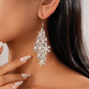 Close-up of sparkling silver snowflake drop earrings with rhinestones on a female model