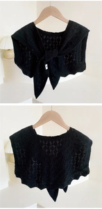 Detail of black knitted shawl featuring hollow weave texture and front tie bow design