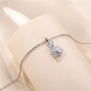 Elegant silver leaf necklace with pear-shaped zircon and baguette stones on beige fabric