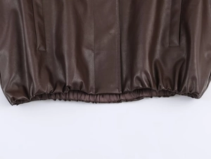 Detailed view of dark brown leather jacket with elastic hem and smooth texture