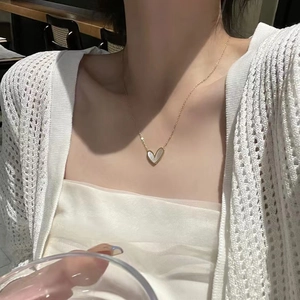 Gold heart shell necklace with delicate chain worn by model in a natural lifestyle setting