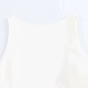 Detailed close-up of the clean neckline and sleeveless cut of the white slim dress