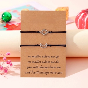 Detail of sun and moon charm bracelets on gift card for best friends with warm pink decor