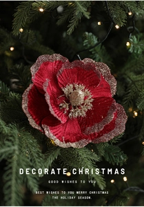Close-up of a red velvet Christmas flower with gold glitter edges on a pine tree