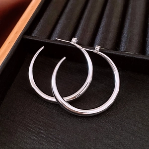 Close-up of polished silver hoop earrings on a black velvet professional display tray