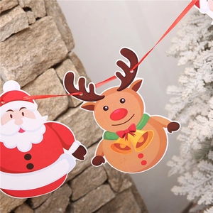 Close-up of paper Christmas banner with Santa and reindeer hanging on stone wall