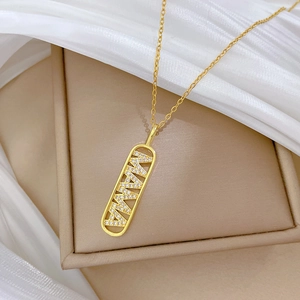 Dettaglio della collana dorata MAMA con diamanti incastonati su scatola beige