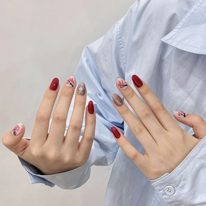 Hand-painted press-on nails in red and silver glitter with cherry blossom design