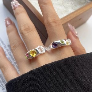 Detail of 925 sterling silver rings with colorful heart and oval stones on a model