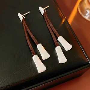 Detailed macro shot of vintage brown leather fringe earrings with white metal accents