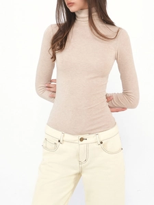 Detailed close-up of oatmeal wool-blend turtleneck showing soft knitted texture and slim fit
