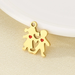 Gold stainless steel boy and girl pendant with red hearts on a beige fabric background