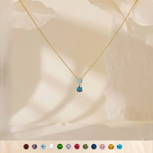Macro detail of 18K gold-plated necklace with light blue and dark blue birthstone teardrop