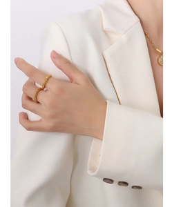 Détail d'une bague multicouche plaquée or 18K avec texture ondulée et collier de pièces