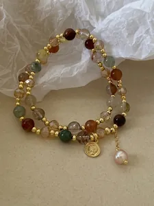 Detail of double-layer beaded bracelet with pink pearl and vintage coin charm