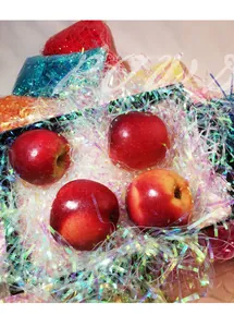 Iridescent shredded raffia paper filling for gift boxes with red apples display