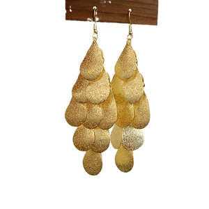 Élégantes boucles d'oreilles dorées à étages avec finition mate sur support en bois