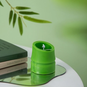 Macro detail of a green bamboo-shaped scented candle on a mirror with natural decor