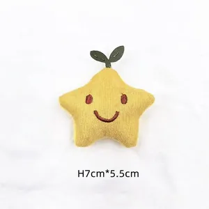 Detailed view of yellow plush star brooch with embroidered smile, size 7cm by 5.5cm