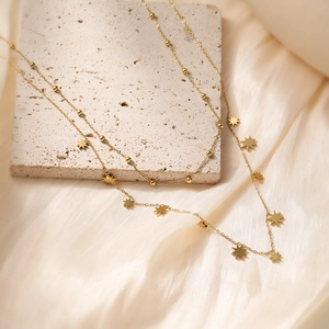 18K gold plated stainless steel necklace with star charms and beads on silk background