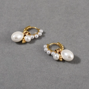 Detailed macro view of gold hoops with large white pearls and small accent beads