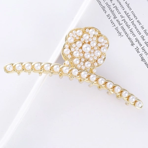 Detail shot of a metal hair claw with white pearls and rose design on a book