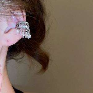 Gros plan d'un ear cuff argenté avec pampilles en zircon brillant sur l'oreille