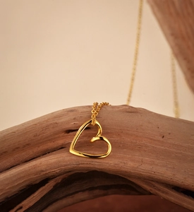 Close-up of minimalist gold heart pendant necklace on natural wood texture
