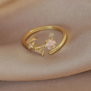 Detailed macro view of gold-plated flower ring with pink enamel and sparkling zircon leaves