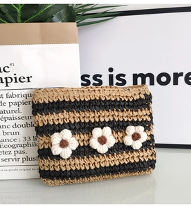 Detailed texture of striped crochet straw envelope bag with white flower decorations