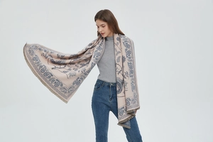 Detail of beige and blue paisley pashmina shawl with fringes on female model