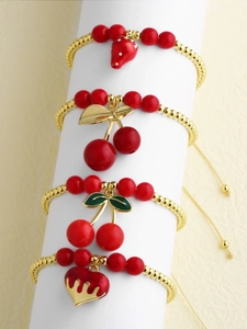 Close-up of 18k gold plated beaded bracelets with red cherry strawberry and heart charms