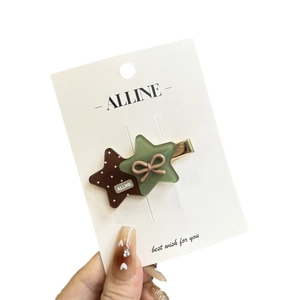 Star-shaped hair clips with brown polka dots and green bows on a metal base