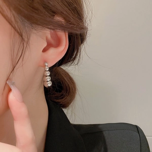 Detailed view of silver beaded drop earrings with four graduated polished metal spheres